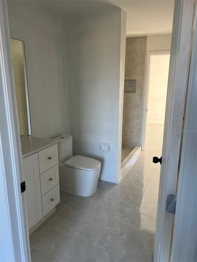 bathroom with vanity, toilet, and a tile shower