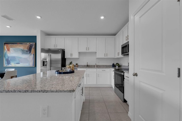 kitchen with white cabinetry, light tile patterned floors, stainless steel appliances, and a kitchen island