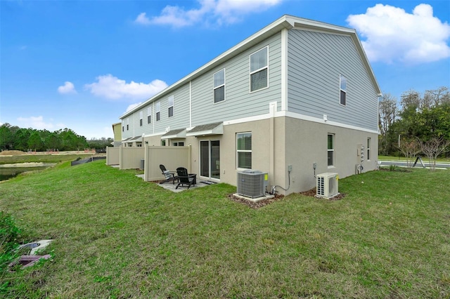 rear view of house with a patio, ac unit, a yard, and central air condition unit