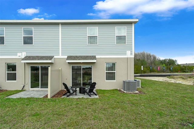 rear view of property featuring central air condition unit, a patio area, and a lawn