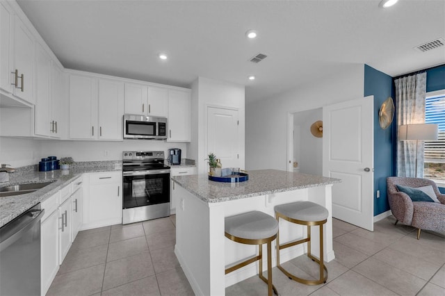 kitchen with white cabinetry, a center island, appliances with stainless steel finishes, and sink