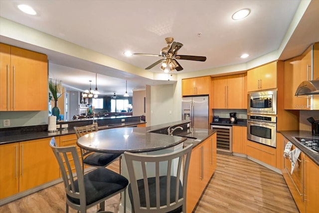 kitchen featuring appliances with stainless steel finishes, ceiling fan with notable chandelier, beverage cooler, sink, and decorative light fixtures