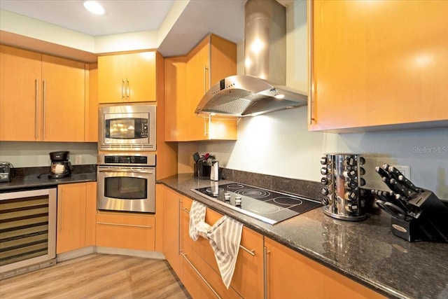 kitchen with beverage cooler, range hood, dark stone counters, appliances with stainless steel finishes, and light wood-type flooring