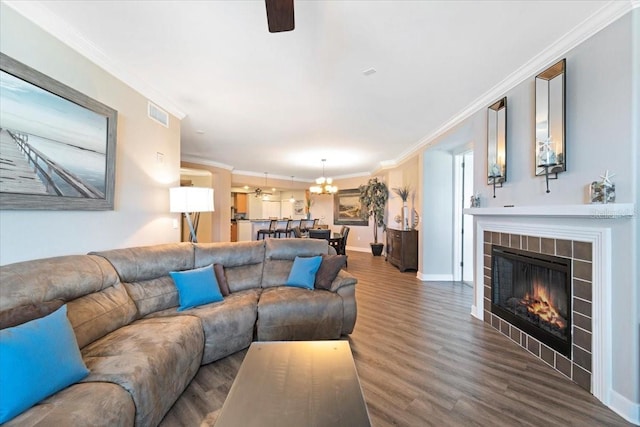 living room with ceiling fan, dark hardwood / wood-style flooring, crown molding, and a tile fireplace