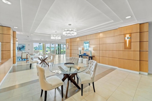 tiled dining room with a raised ceiling, wood walls, and an inviting chandelier