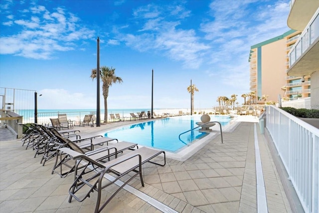 view of pool with a water view and a patio