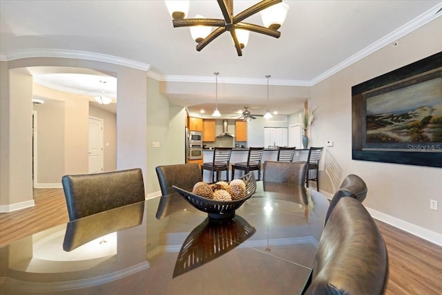 dining room with hardwood / wood-style floors, ceiling fan with notable chandelier, and crown molding