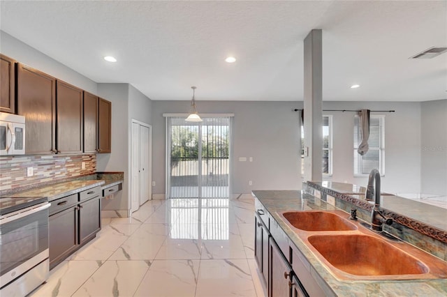 kitchen featuring sink, hanging light fixtures, stainless steel appliances, decorative backsplash, and dark brown cabinets