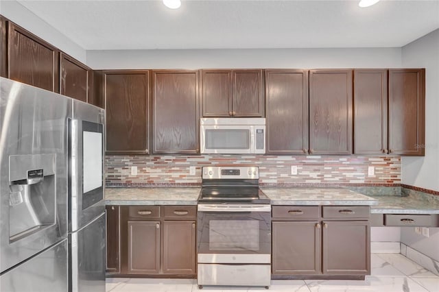 kitchen featuring dark brown cabinets, backsplash, stainless steel appliances, and dark stone countertops