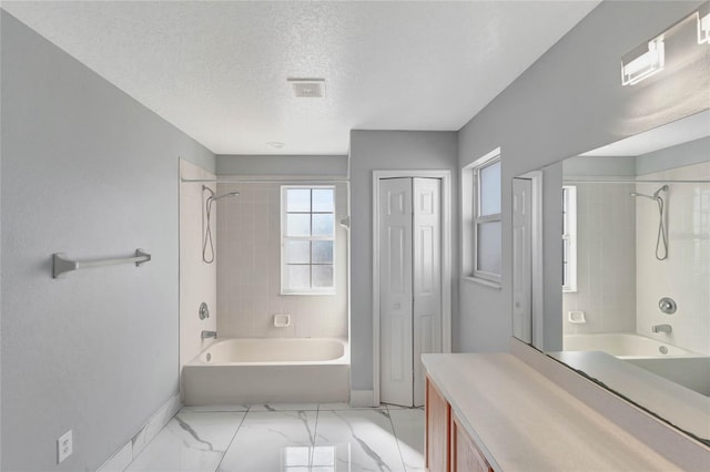 bathroom featuring a textured ceiling, vanity, and tiled shower / bath