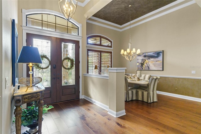 foyer entrance featuring hardwood / wood-style floors, crown molding, french doors, and a notable chandelier