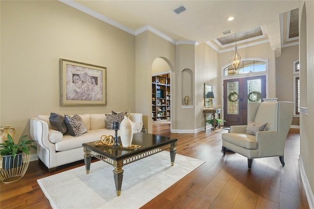 living room with wood-type flooring, crown molding, and a high ceiling