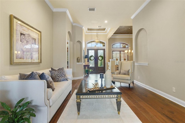 living room featuring dark hardwood / wood-style flooring, french doors, crown molding, and an inviting chandelier