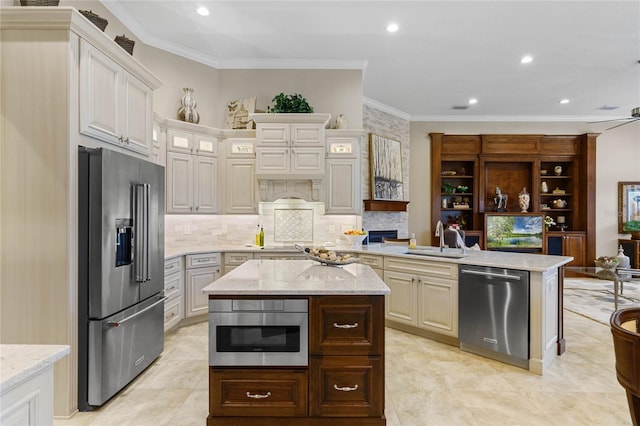 kitchen with sink, stainless steel appliances, light stone counters, crown molding, and a kitchen island