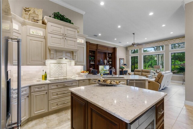 kitchen with light stone counters, cream cabinets, ceiling fan, and sink