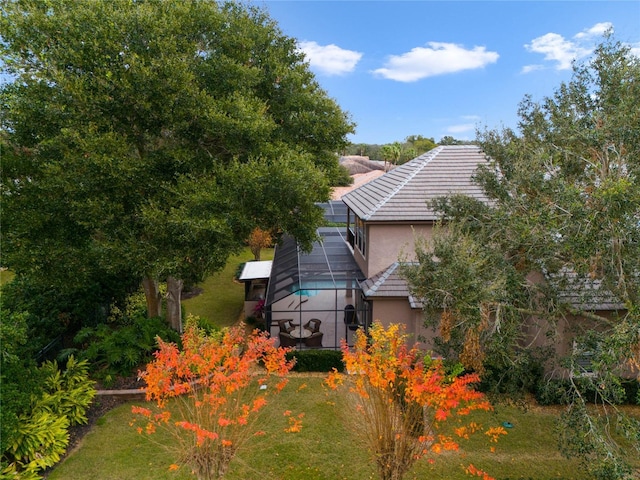 back of property with glass enclosure and a lawn