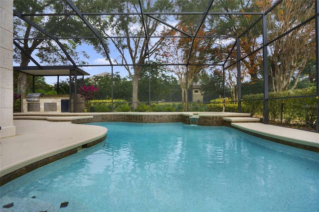 view of swimming pool with glass enclosure, a patio area, area for grilling, and an outdoor kitchen