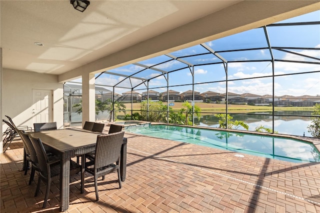 view of pool with an in ground hot tub, a water view, glass enclosure, and a patio area