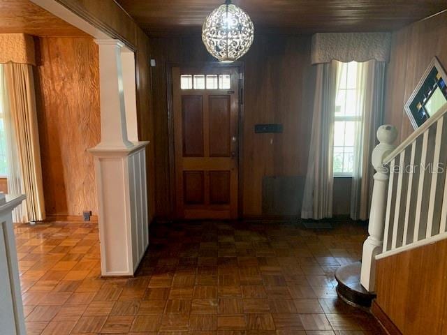 foyer featuring a notable chandelier, dark parquet floors, wooden ceiling, and wooden walls