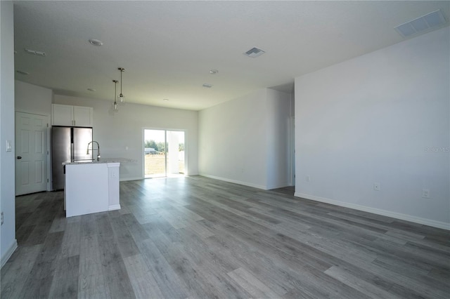 unfurnished living room featuring wood-type flooring and sink