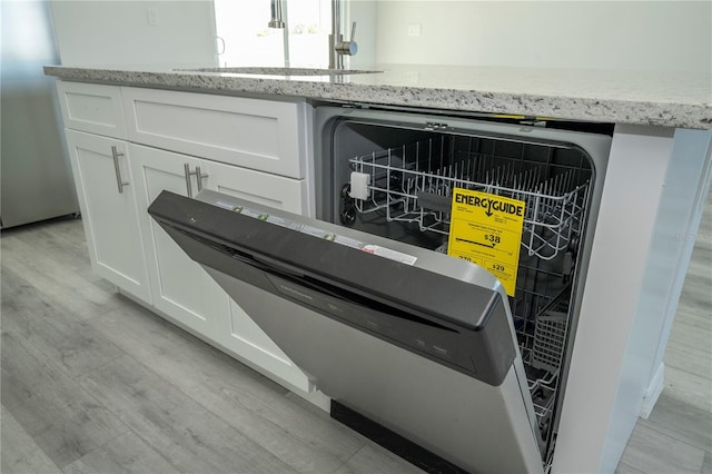 room details featuring white cabinets, dishwashing machine, sink, and light hardwood / wood-style flooring