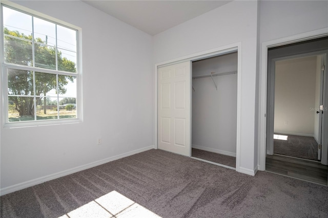 unfurnished bedroom with dark carpet, a closet, and multiple windows