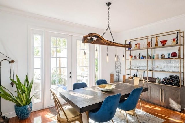 dining space featuring french doors, ornamental molding, and hardwood / wood-style flooring