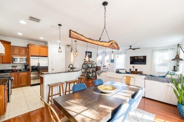 dining space featuring light wood-type flooring, plenty of natural light, ceiling fan, and ornamental molding