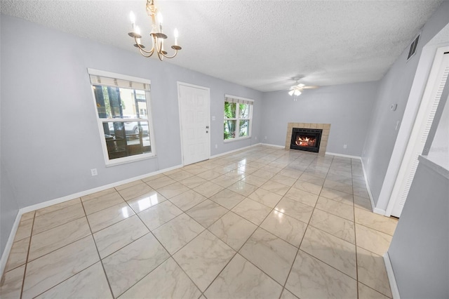 unfurnished living room with a fireplace, light tile patterned floors, a textured ceiling, and ceiling fan with notable chandelier