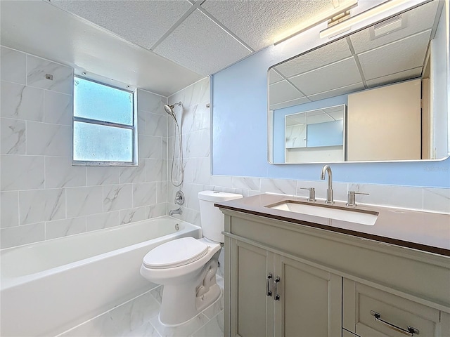 full bathroom featuring toilet, a drop ceiling, vanity, and tiled shower / bath