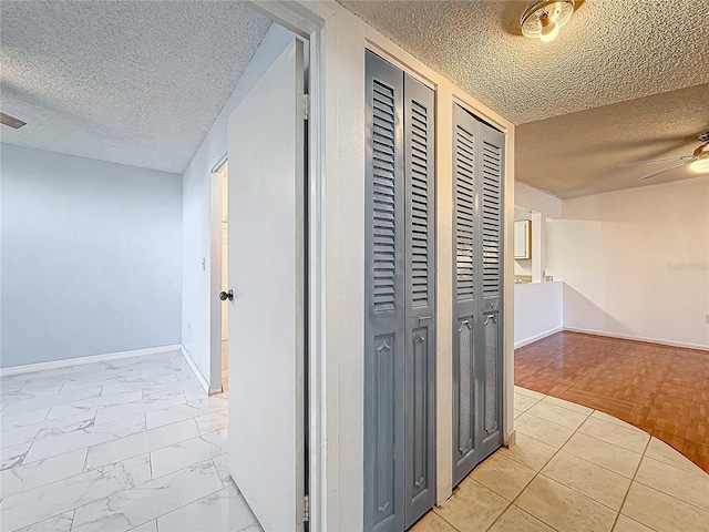 hall with light wood-type flooring and a textured ceiling