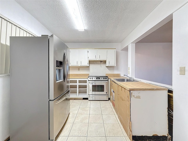 kitchen featuring sink, light tile patterned floors, a textured ceiling, white cabinets, and appliances with stainless steel finishes