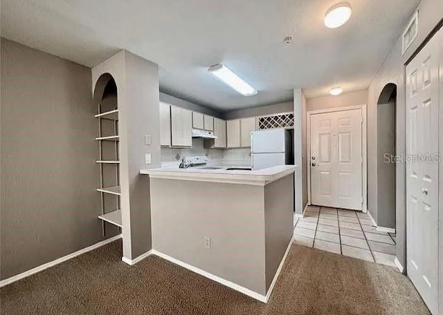 kitchen featuring white refrigerator, stainless steel range oven, white cabinetry, light colored carpet, and kitchen peninsula