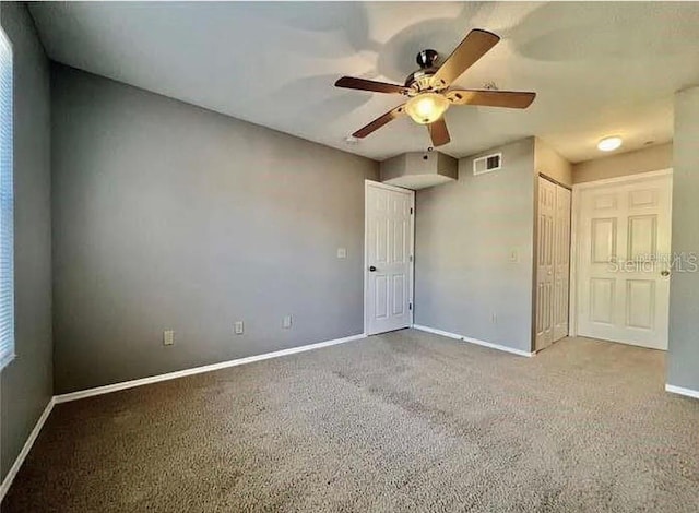 empty room featuring ceiling fan and light colored carpet