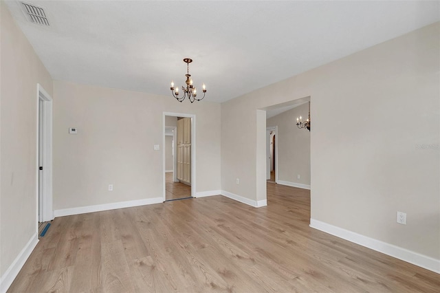 spare room featuring a chandelier and light hardwood / wood-style flooring