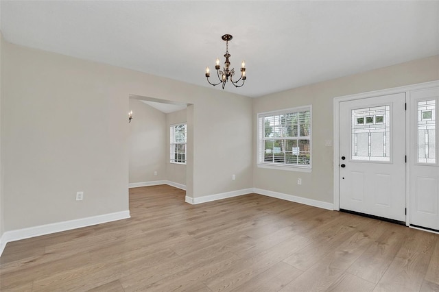 entryway featuring plenty of natural light, a notable chandelier, and light wood-type flooring