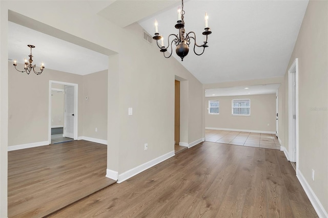 unfurnished dining area with light wood-type flooring, lofted ceiling, and an inviting chandelier