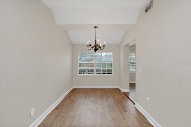 unfurnished dining area with light hardwood / wood-style flooring, lofted ceiling, and a notable chandelier