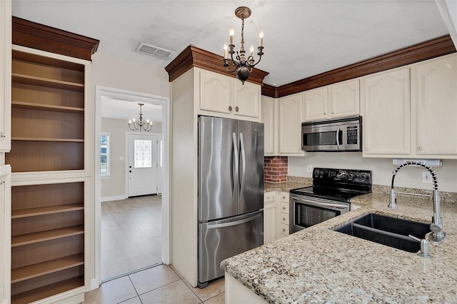 kitchen featuring sink, light stone counters, a chandelier, decorative light fixtures, and appliances with stainless steel finishes