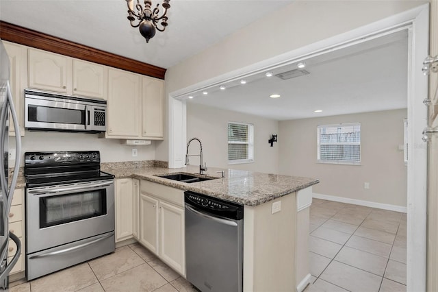 kitchen featuring kitchen peninsula, appliances with stainless steel finishes, light stone counters, sink, and light tile patterned flooring