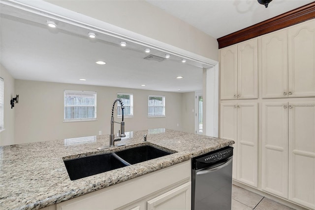 kitchen featuring light stone countertops, sink, light tile patterned floors, stainless steel dishwasher, and white cabinets