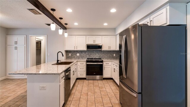 kitchen featuring kitchen peninsula, stainless steel appliances, sink, white cabinets, and hanging light fixtures