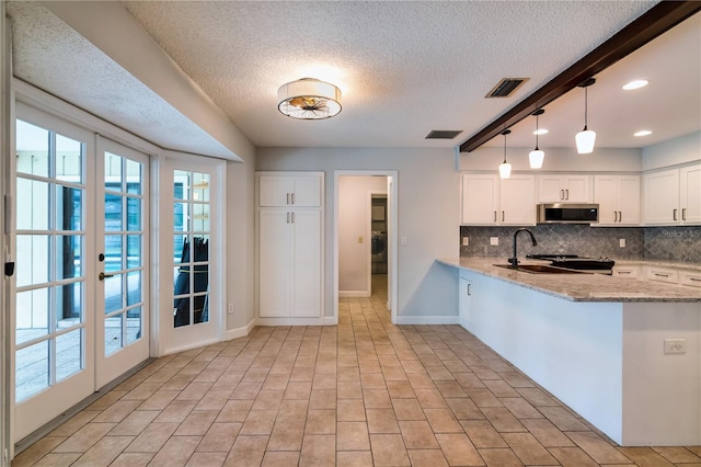 kitchen featuring light stone countertops, white cabinetry, kitchen peninsula, and french doors