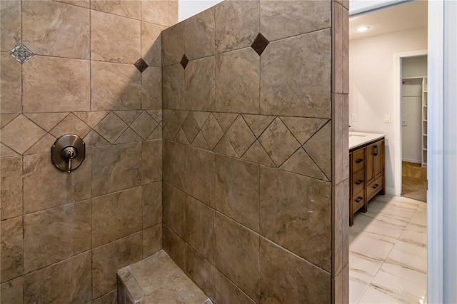 bathroom with a tile shower and vanity