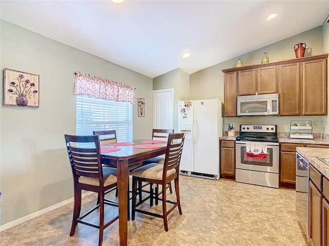 kitchen featuring appliances with stainless steel finishes, lofted ceiling, and light tile patterned flooring