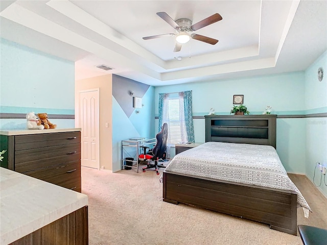 carpeted bedroom with a tray ceiling, ceiling fan, and a closet