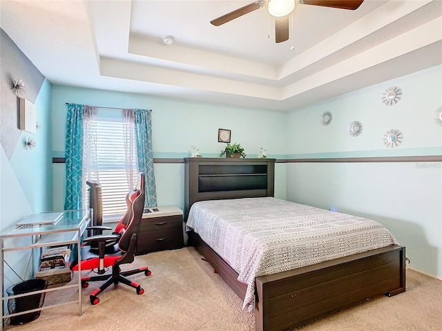 carpeted bedroom featuring ceiling fan and a tray ceiling