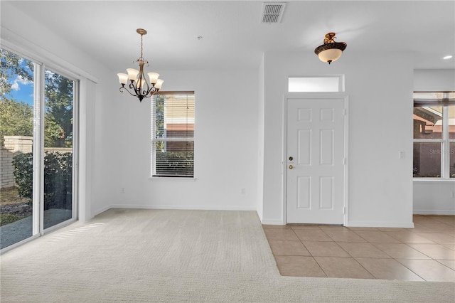 foyer featuring a chandelier, a wealth of natural light, and light carpet