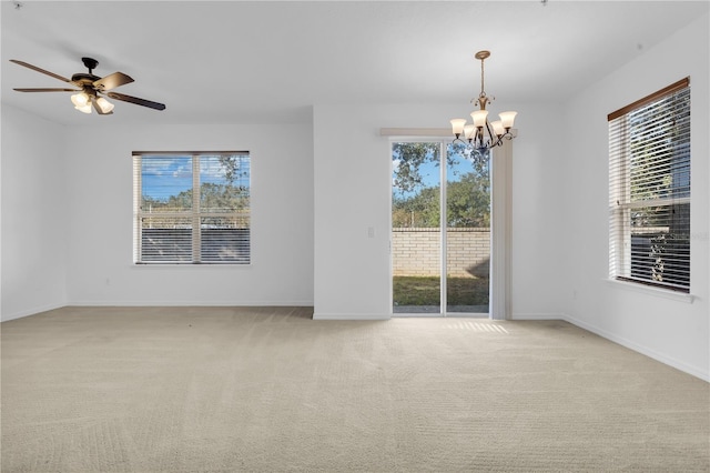 carpeted empty room with plenty of natural light and ceiling fan with notable chandelier