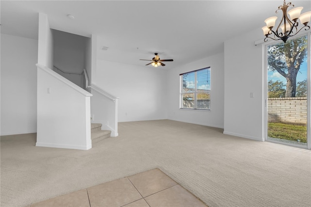 unfurnished living room with ceiling fan with notable chandelier and light colored carpet